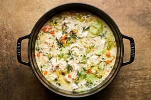 A pot of creamy chicken and rice soup, elegantly topped with fresh dill and black pepper for an extra touch of flavor.