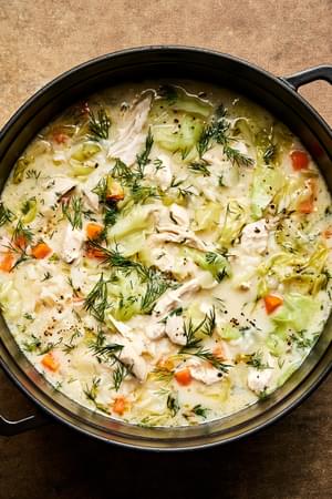 A pot of creamy chicken and rice soup, elegantly topped with fresh dill and black pepper for an extra touch of flavor.