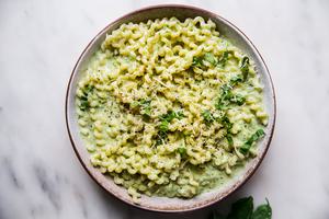 creamy zucchini pasta sauce with spiral pasta in a bowl with parmesan cheese and fresh basil.