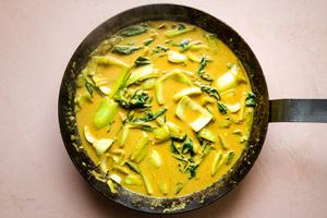 Creamy Curry sauce with bok choy and green onions in a saucepan