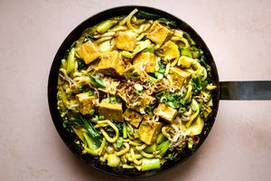 Crispy Tofu with Creamy Curry Udon Noodles in a sauce pan with fried shallots, baby bok choy, and green onions