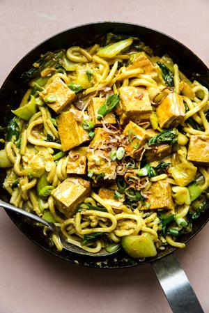 Crispy Tofu with Creamy Curry Udon Noodles in a sauce pan with fried shallots, baby bok choy, and green onions