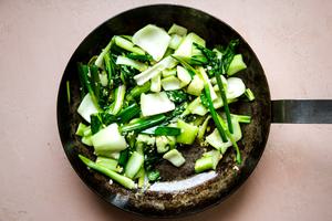 baby bok choy and green onions in a frying pan with canola oil