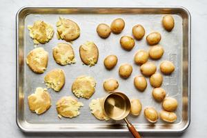 boiled potatoes being smashed on a baking sheet