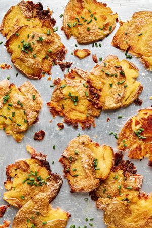crispy smashed potatoes seasoned with salt and garlic sprinkled and with chives on a baking sheet