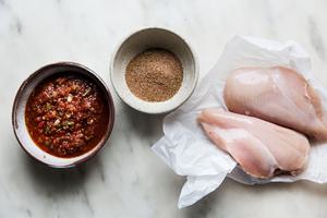 salsa, a bowl of taco seasoning and two chicken breasts shown next to each other on a marble surface for chicken taco meet