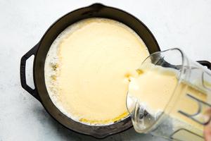 Dutch Baby pancake batter being poured into a hot cast iron skillet