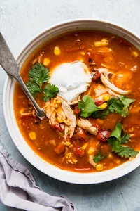 5 ingredient chicken tortilla soup in a bowl with cilantro and sour cream