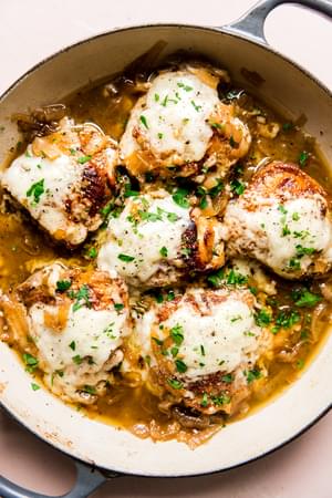 French onion chicken in a braiser with gruyere cheese and caramelized onions