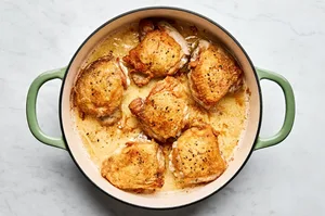 chicken thighs seasoned with salt and pepper being browned in olive oil in a skillet