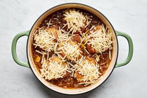 french onion chicken in a skillet being topped with Gruyère