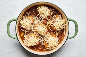 french onion chicken in a skillet being topped with Gruyère