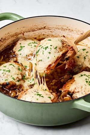 french onion chicken topped with Gruyère cheese being scooped out of a skillet