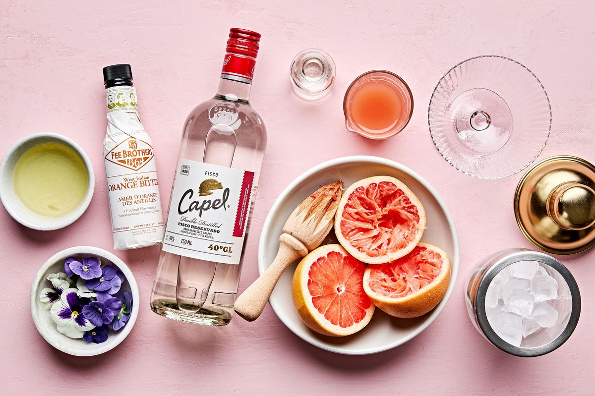 ingredients laid out for a Grapefruit Pisco Sour with Orange Bitters cocktail: pisco, grapefruit juice and bitters