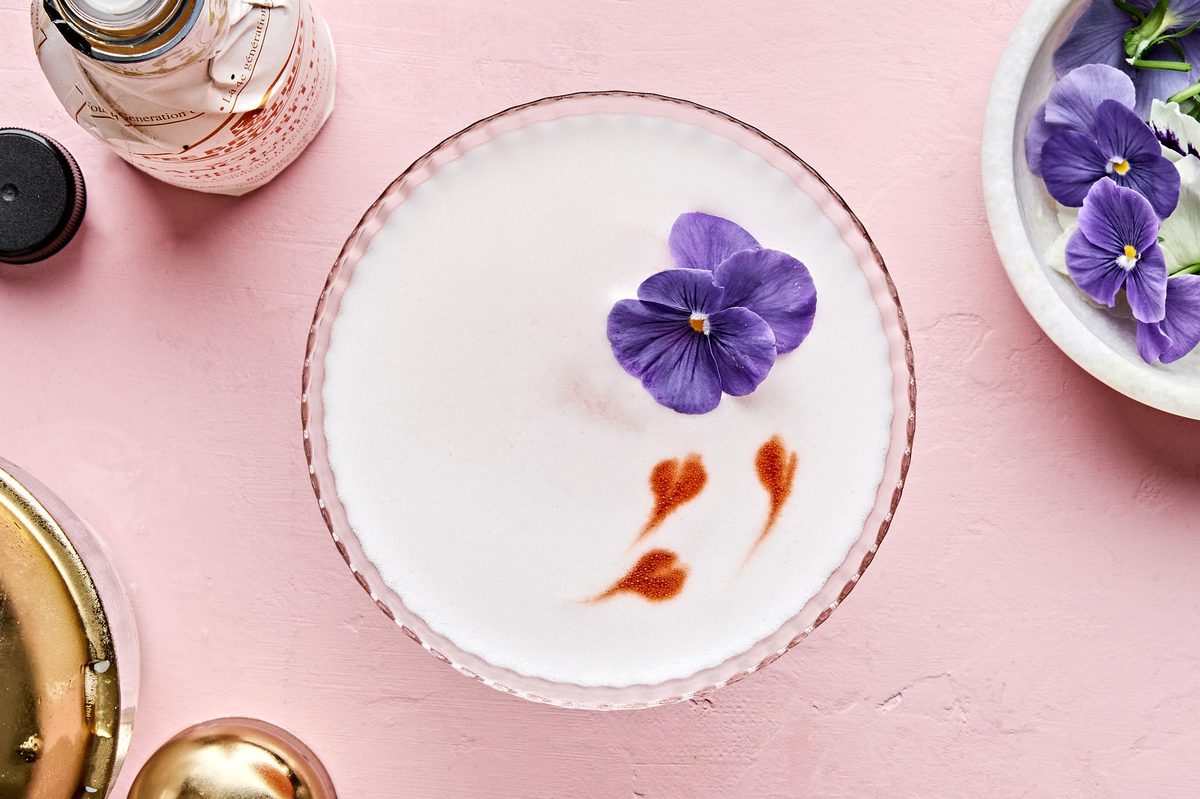 a grapefruit pisco sour with orange bitters cocktail garnished with a flower