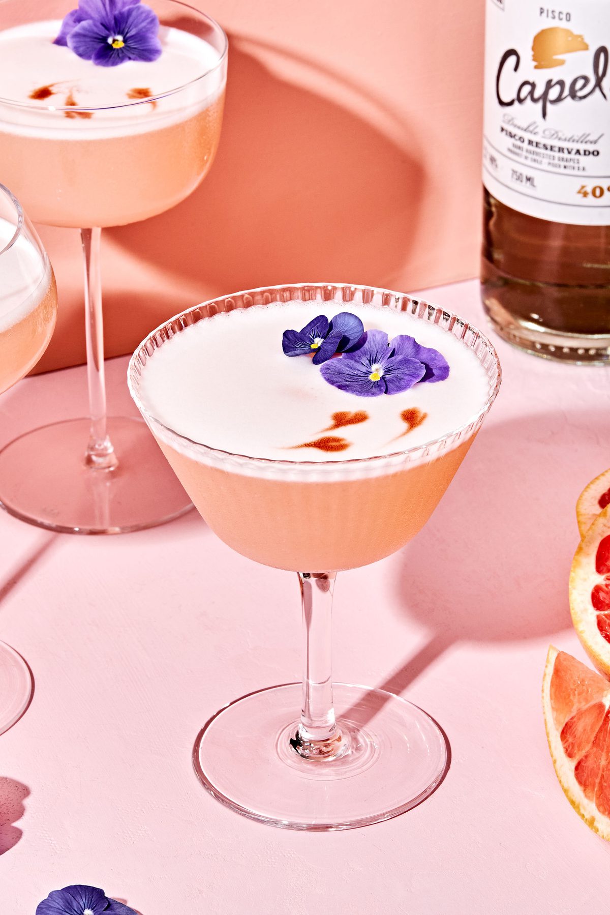 a grapefruit pisco sour with orange bitters garnished with a flower