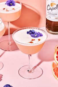 a grapefruit pisco sour with orange bitters garnished with a flower