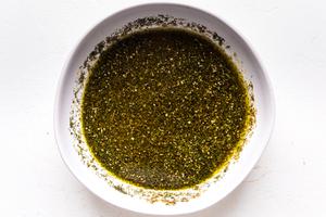 Greek Chicken marinade in a small bowl with dill, garlic, oregano and olive oil for a freezer meal