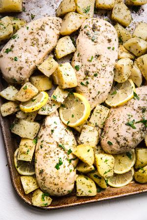4 Greek flavored Chicken breast with potatoes, olive oil, lemon oregano, garlic, dill on a sheet pan.