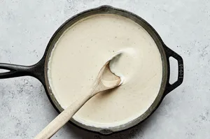 cream sauce being stirred in a skillet made with butter, flour, half and half, spices, mustard and stock