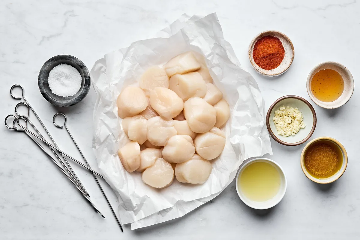 Fresh sea scallops with cooking ingredients and metal skewers for grilled scallops recipe preparation