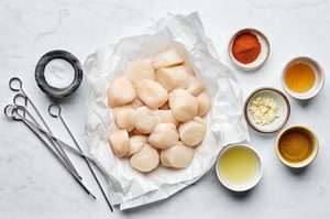 Fresh sea scallops with cooking ingredients and metal skewers for grilled scallops recipe preparation