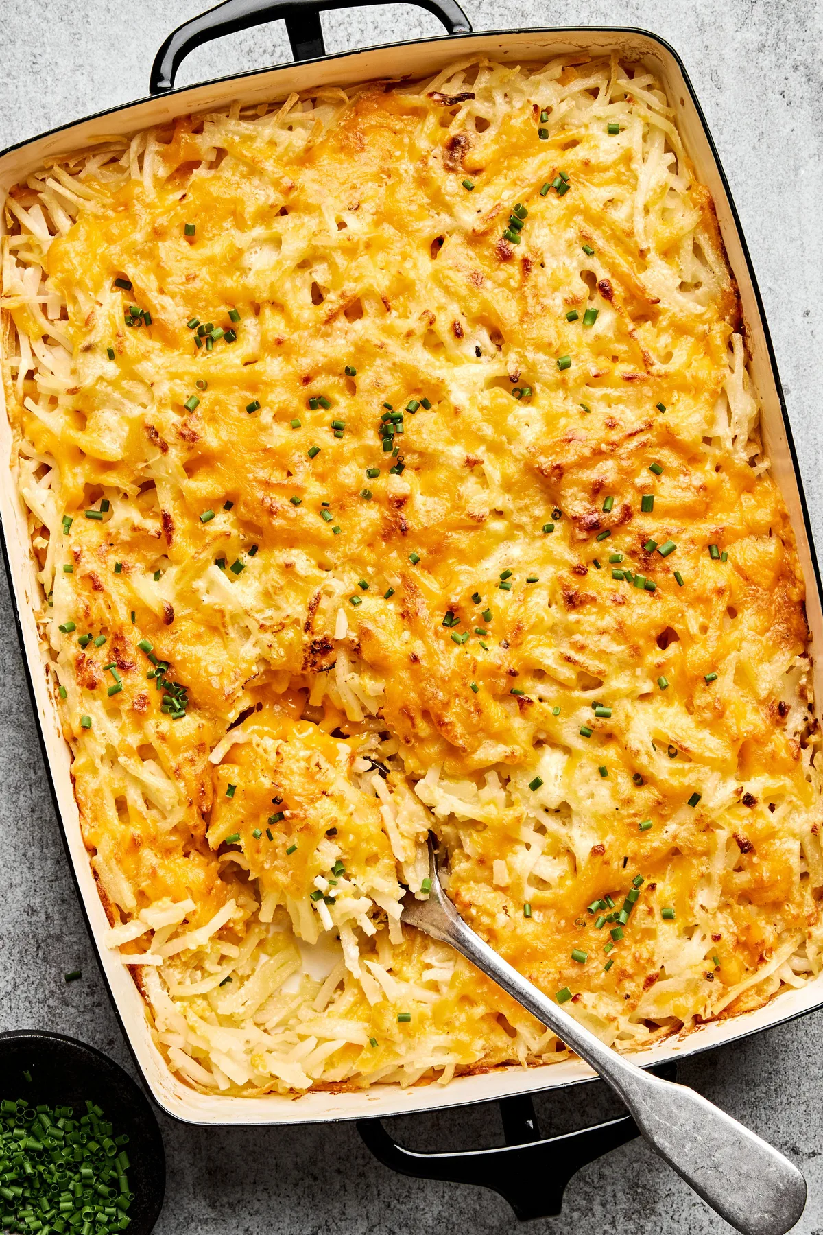 A golden-brown hashbrown casserole topped with melted cheese in a list of the best potato dish breakfast ideas