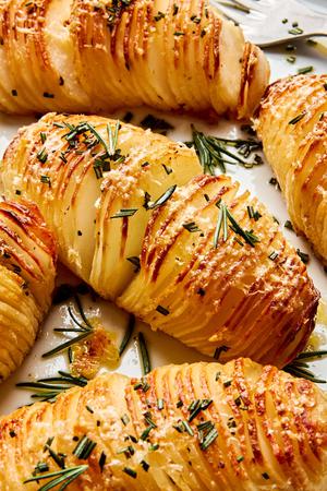 a platter of hasselback potatoes made with herb butter and topped with Parmesan and rosemary