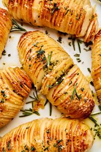 hasselback potatoes made with butter, shallot, garlic, rosemary, salt and parmesan on a serving plate
