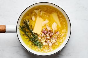 butter, olive oil, shallot, garlic, and rosemary sprigs cooking in a pot