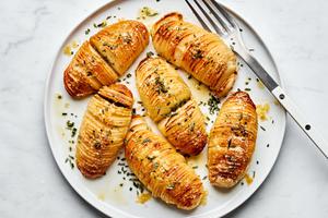 a platter of hasselback potatoes made with herb butter and topped with Parmesan and rosemary