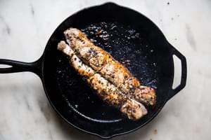 Herb crusted Pork Tenderloin browned on all sides in a cast iron pan
