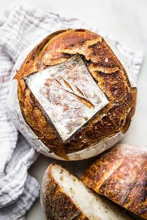 two sourdough bread boules show on a white linen