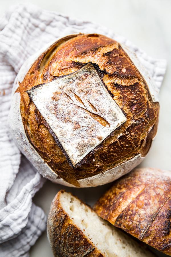 two sourdough bread boules show on a white linen
