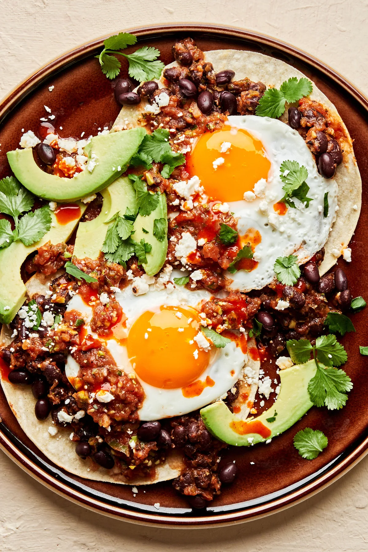 a plate of huevos rancheros topped with avocado and cilantro in a list of easy tex-mex brunch classic recipes