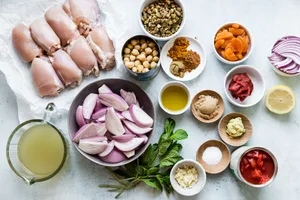 chicken thighs, chicken stock, shallots, tomatoes, dried fruit, chickpeas and herbs in small bowls for chicken tagine