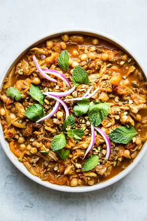 Instant pot chicken tagine in a white bowl topped with fresh herbs