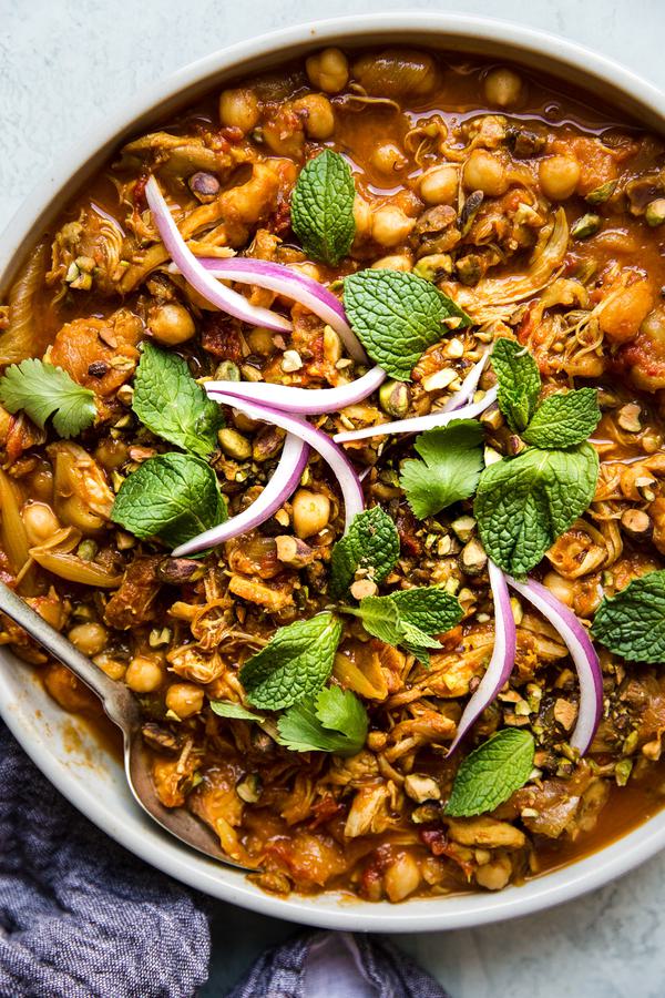 instant pot chicken tagine in a large white bowl topped with fresh mint and cilantro