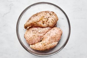 raw chicken breast seasoned with Italian seasoning, garlic powder, brown sugar, salt, and pepper in a bowl