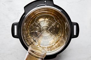 chicken broth being poured into an instant pot with a rack to prep to make chicken breast, a simple healthy protein