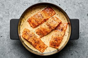 Marry Me Salmon fillets simmering in a creamy, sun-dried tomato sauce inside a skillet
