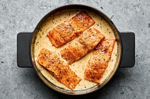 Marry Me Salmon fillets simmering in a creamy, sun-dried tomato sauce inside a skillet
