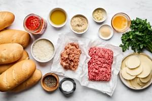 ingredients for meatball sub sandwiches laid out in bowls: ground beef, ground italian sausage, Parm, marinara, and spices