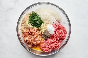 ground beef, ground italian sausage, breadcrumbs, eggs, herbs, spices & Parm being mixed to form the perfect meatballs