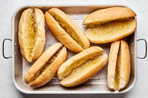 hoagie rolls brushed with olive oil and sprinkled with garlic powder on a baking sheet
