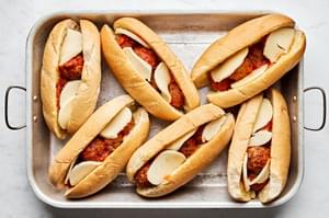 meatball sub sandwiches assembled on a baking sheet and ready to be broiled to get toasted and melty