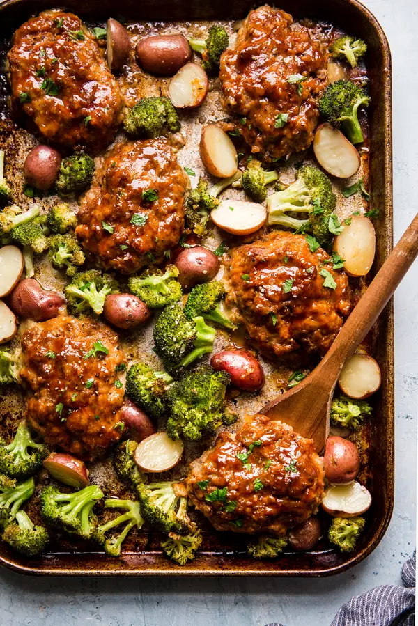 6 Mini Italian Style meat loafs on a sheet pan with broccoli and roasted potatoes.