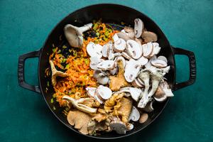 shallot, celery, carrots, garlic and mushrooms being cooked in olive oil in a saucepan for mushroom ragù