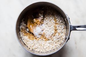 sugar, milk, butter cocoa powder, oats, peanut butter, vanilla and sea salt being stirred together in a saucepan