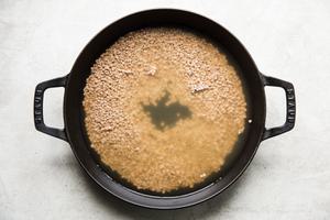 Lentils and chicken stock shown in a large skillet